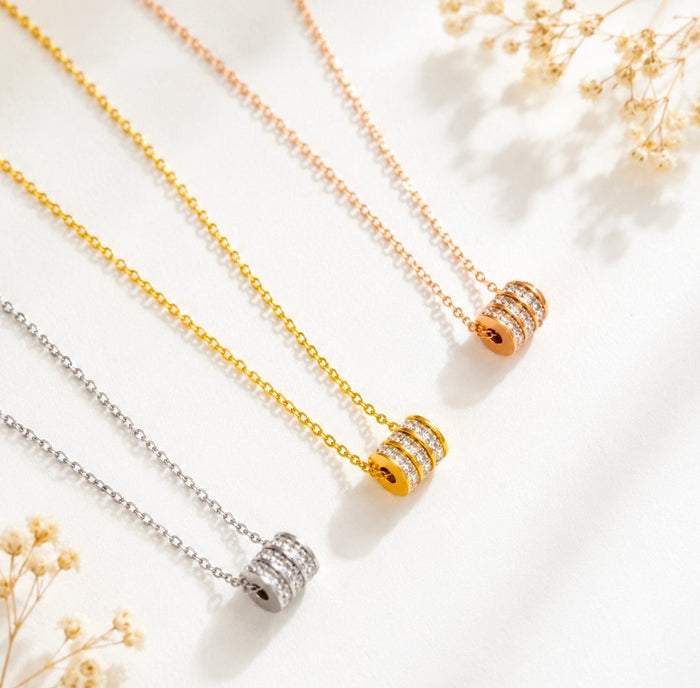 Cubic zirconia pendant necklace collection featuring sleek cylindrical designs in silver, gold, and rose gold styles.