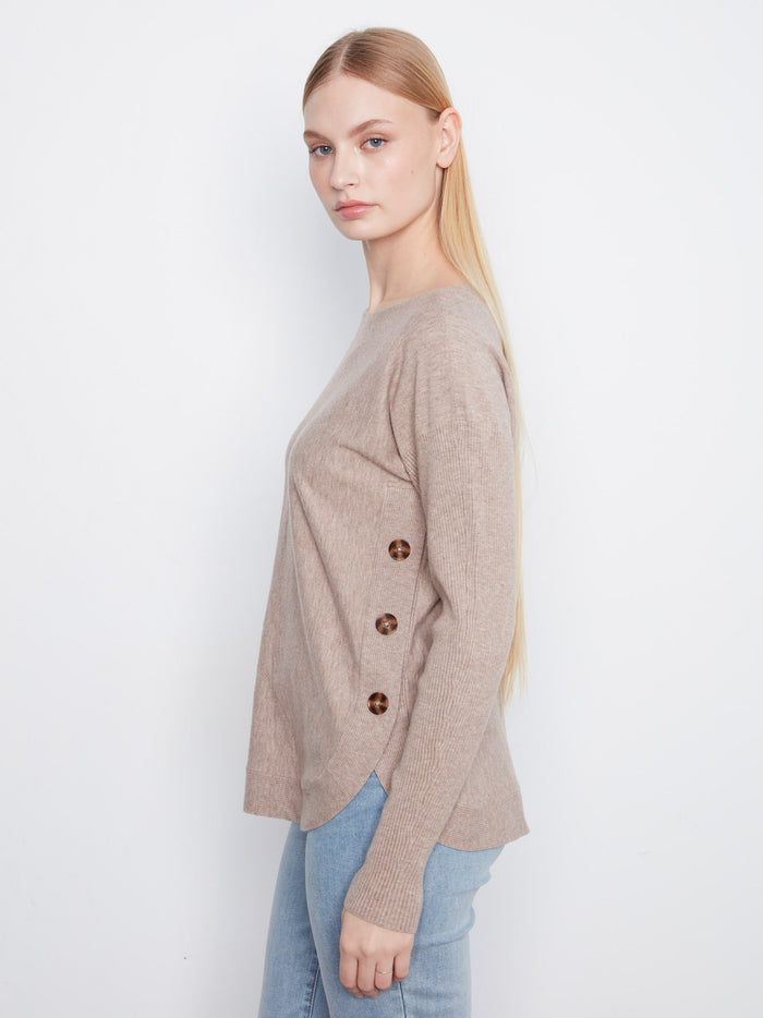 Cozy sweater featuring eye-catching side button details that add a unique touch to the design. By Charlie B.
