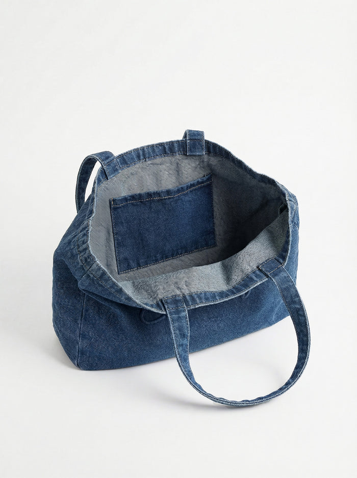 Denim tote showcasing the embossed logo, offering ample space with a 16" length. Designed by Charlie B.