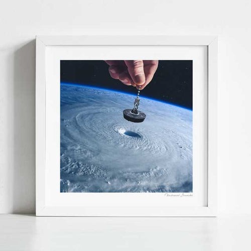 Down the Drain art print framed view — surreal collage of a hand plugging a vast swirling hurricane from orbit to stop the storm, environmental wall art for bold gallery walls and creative spaces