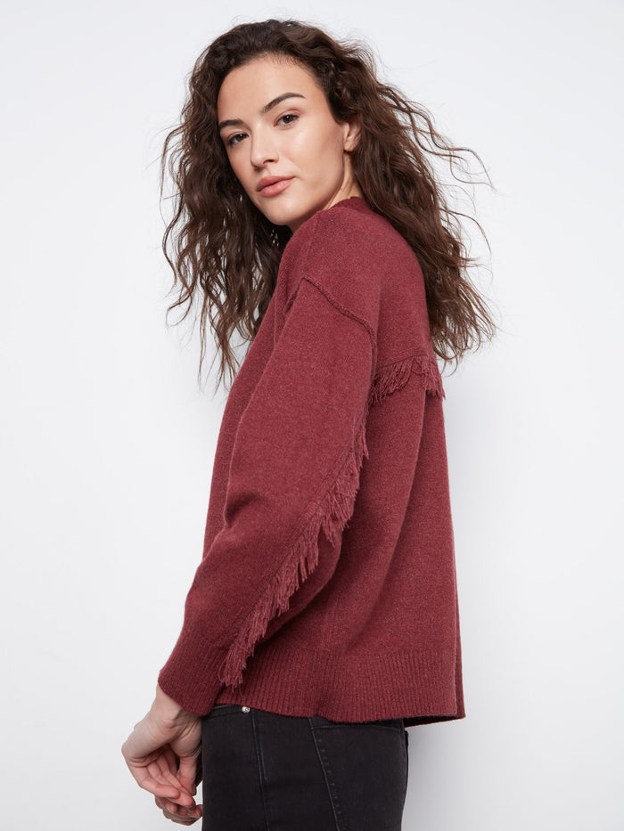 This sweater in Heather-Merlot showcases drop shoulders with fringe detailing, adding a playful touch to your wardrobe by Charlie B.