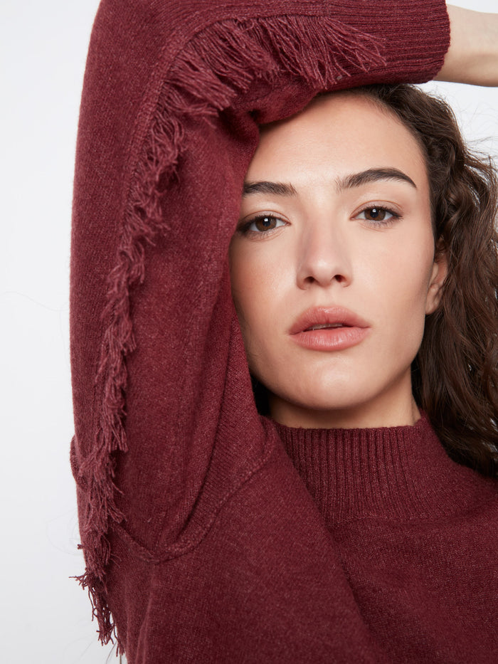 Long sleeve Merlot sweater with unique fringe accents along the arms, combining comfort and fashion effortlessly by Charlie B.