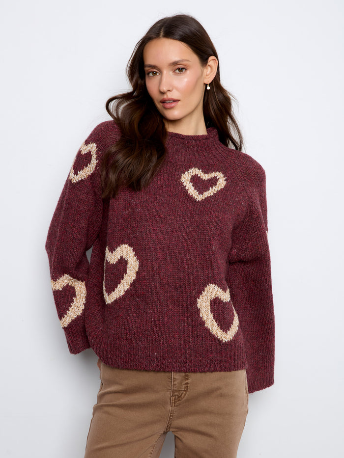 Soft knit sweater showcasing delightful hearts along the 3/4 bell sleeves, blending elegance with playfulness. By Charlie B.